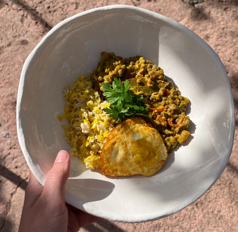 Zoe holding a green lentil dahl with organic turmeric 